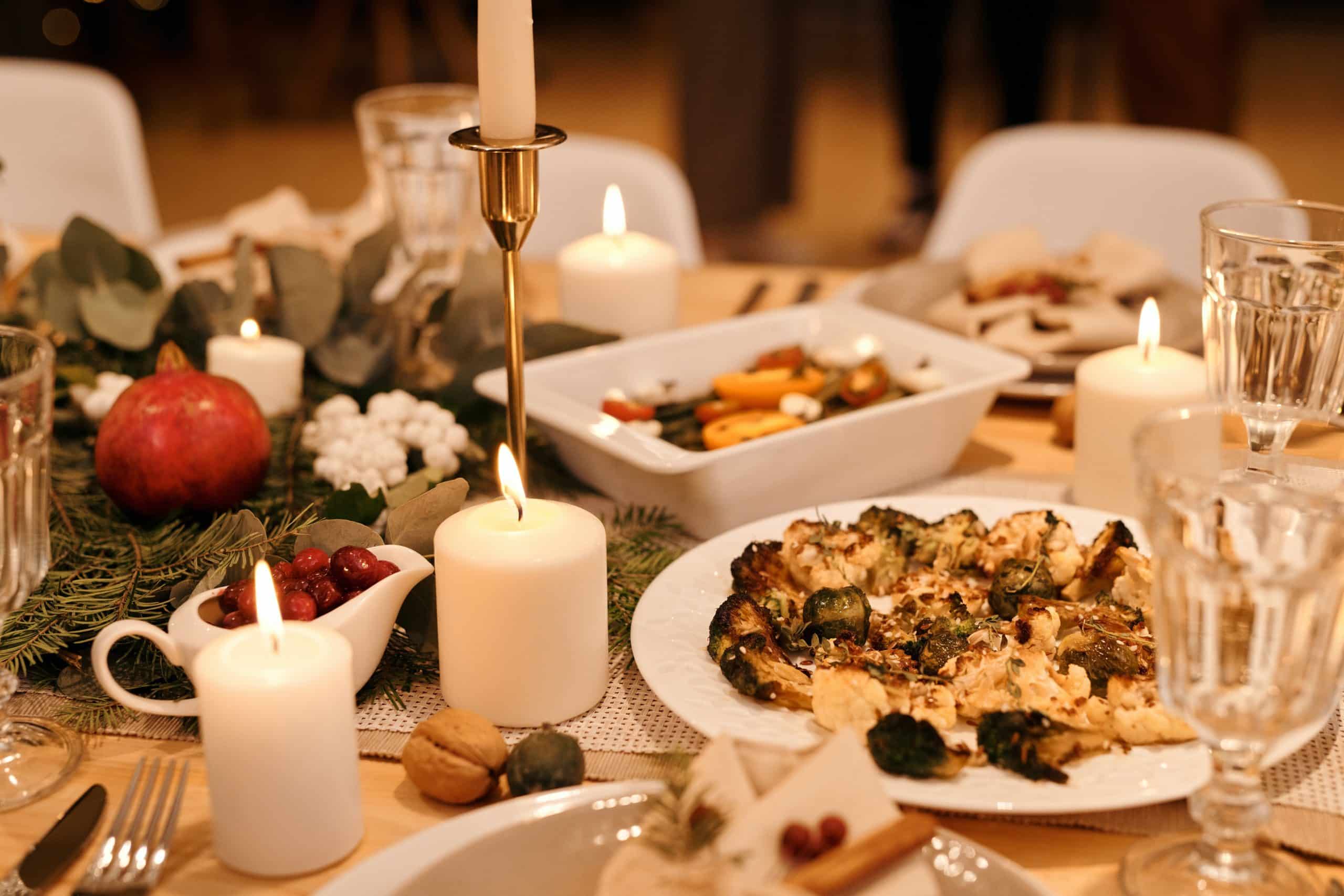 healthy dinner with fruits and vegetables sits on a table with candles & greenery